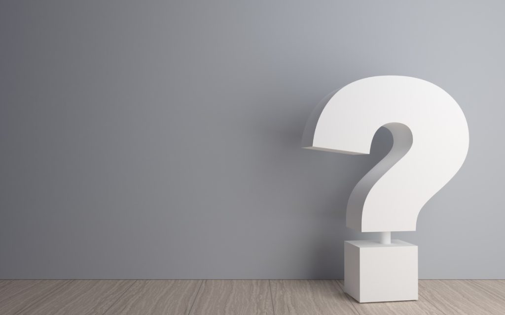 big white question mark in a room with grey wall