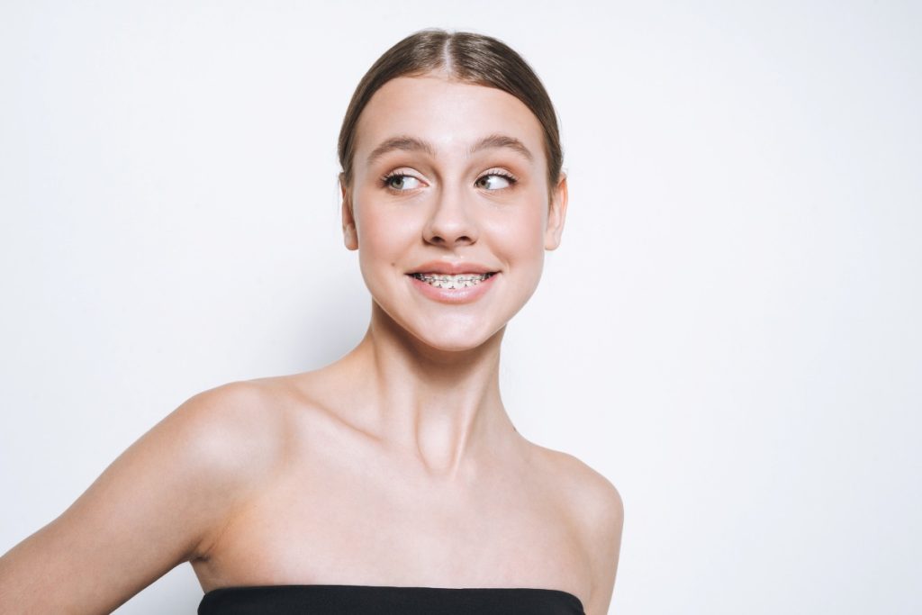teenager with braces on teeth on white background