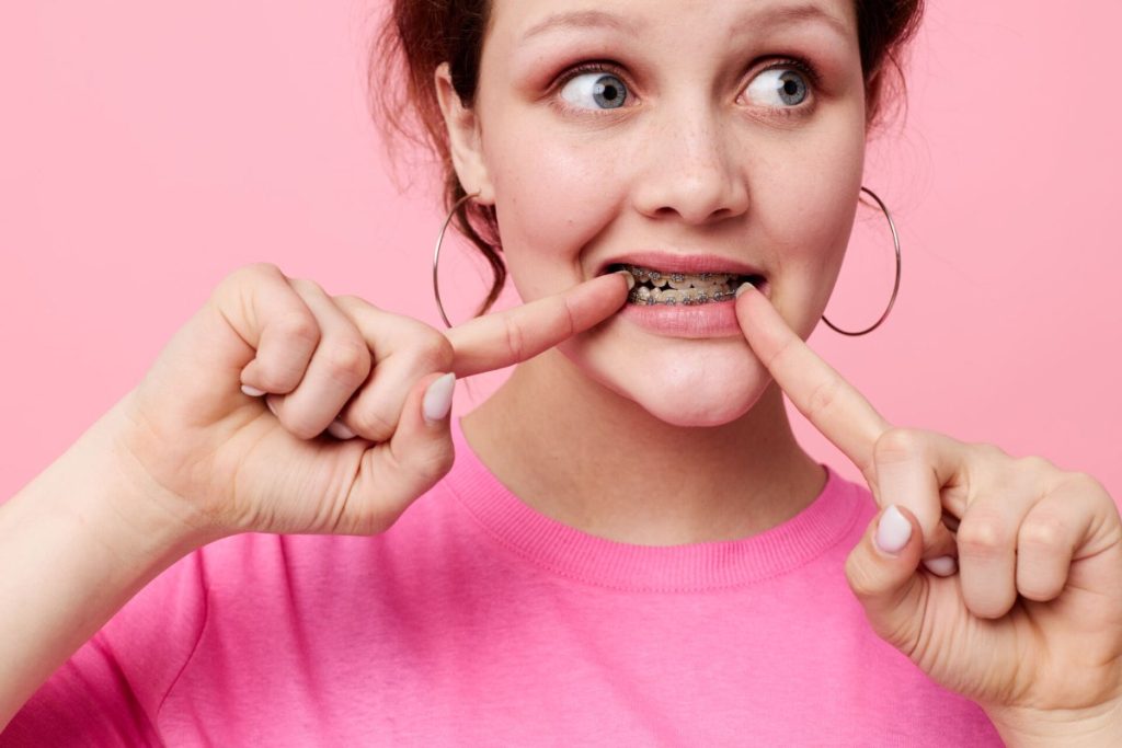 woman with braces posing on pink background
