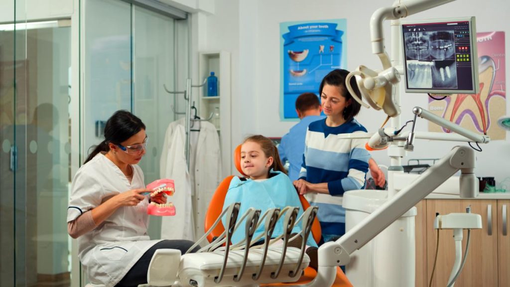 Stomatologist holding plaster model of the mandible speaking with girl patient