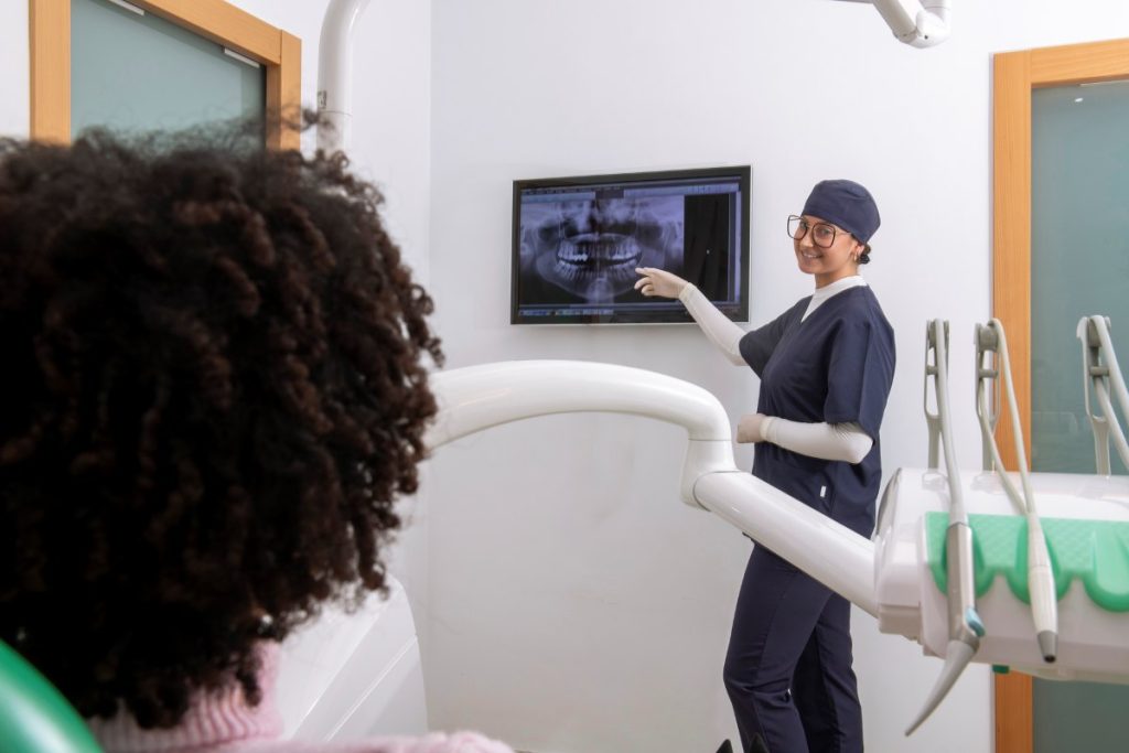 Female dentist showing teeth x ray to patient in dental clinic