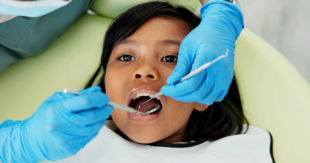 Girl, pediatric dentist and checkup of teeth in chair and family friendly examination for tooth cavities